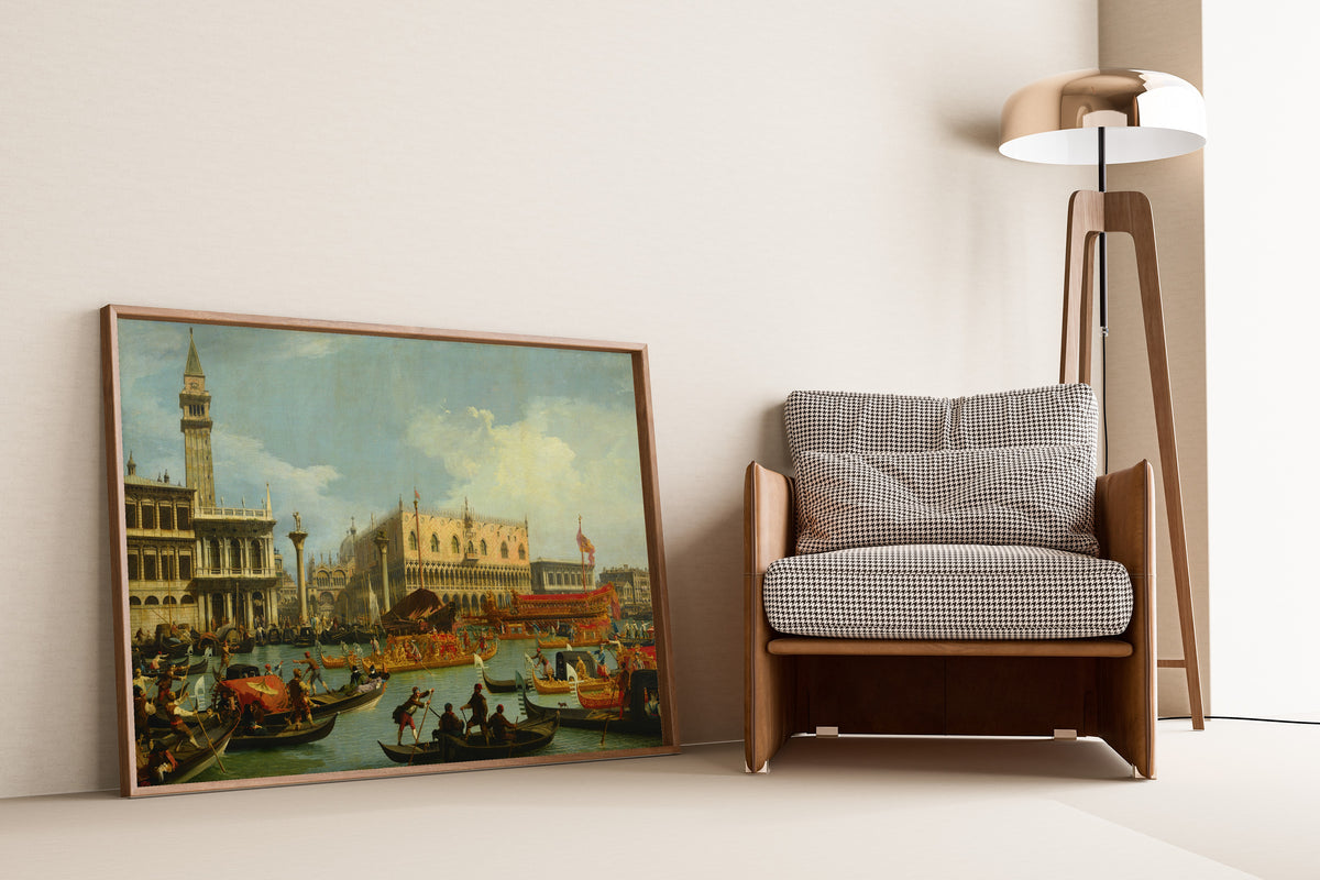 Framed art print of The Bucintore Returning to the Molo on Ascension Day by Canaletto, leaning against a wall beside an armchair and a floor lamp