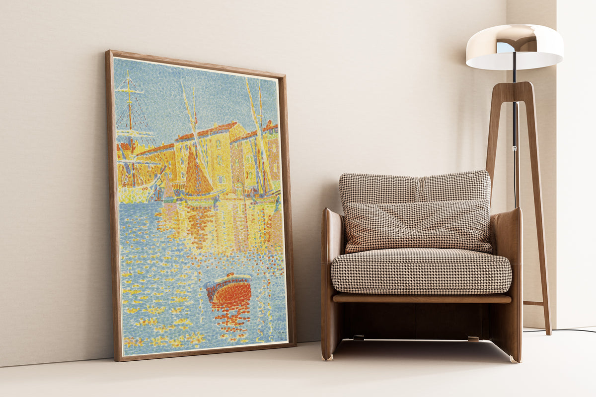 Framed art print of The Buoy by Paul Signac, leaning against a wall beside an armchair and a floor lamp