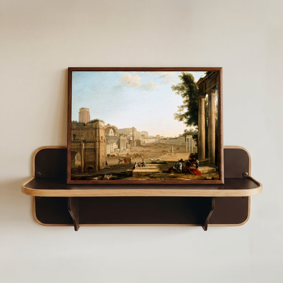 Framed art print of The Campo Vaccino, Rome by Claude Lorrain, in a dark wood frame resting on a wall shelf
