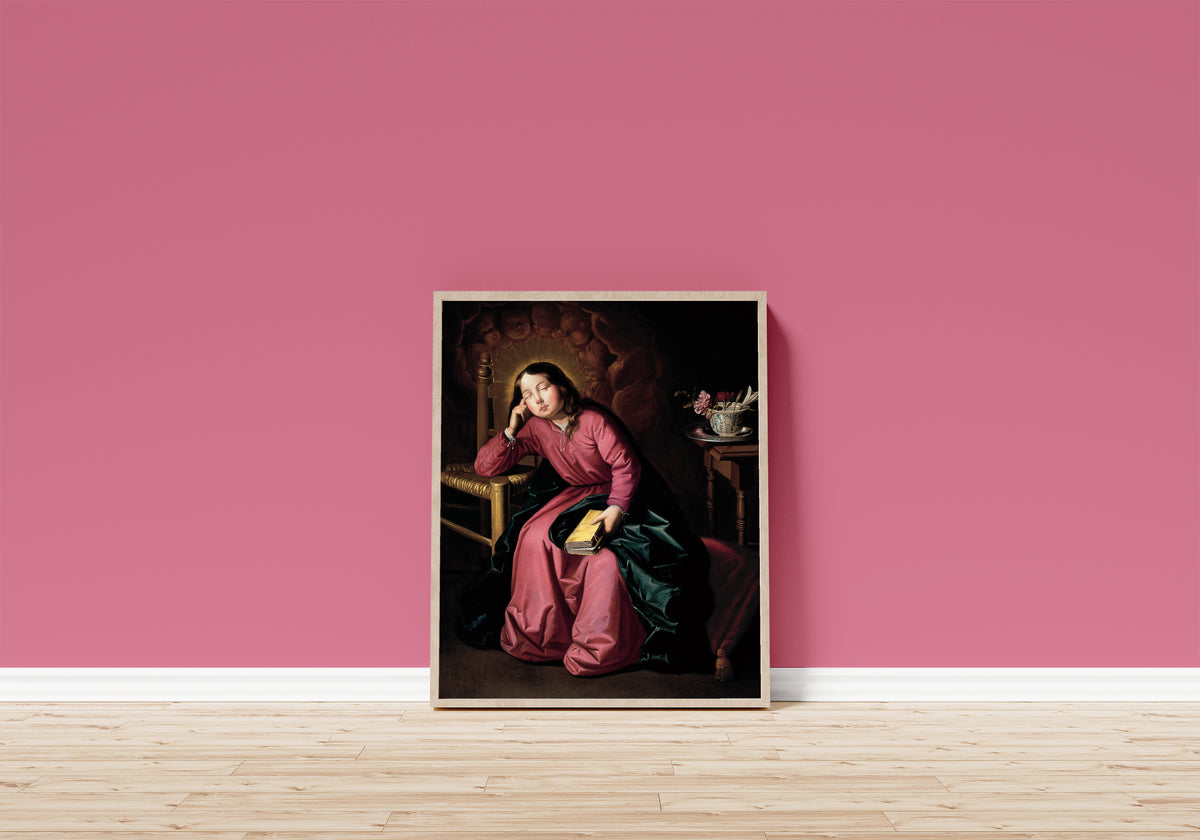 Framed art print of The Child Virgin Asleep by Francisco de Zurbarán, in a light wood frame leaning on a pink wall above a wooden floor
