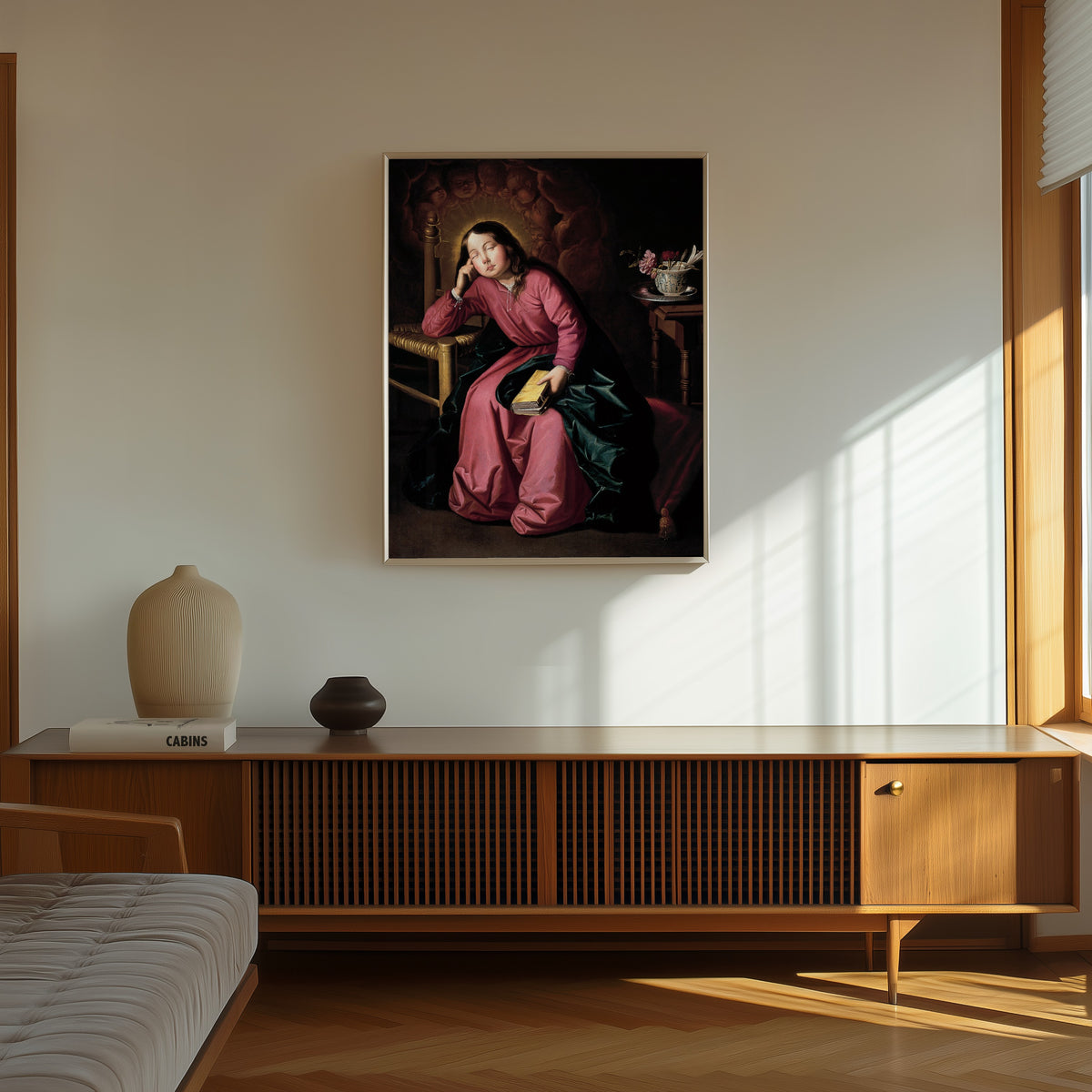 Framed art print of The Child Virgin Asleep by Francisco de Zurbarán, in a thin light frame on a sunlit wall above a wooden sideboard