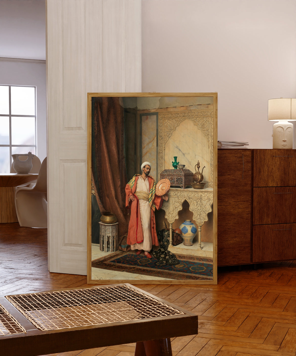 Framed art print of The Connoisseur by Ludwig Deutsch, in a light wood frame leaning in a warm room with a parquet floor