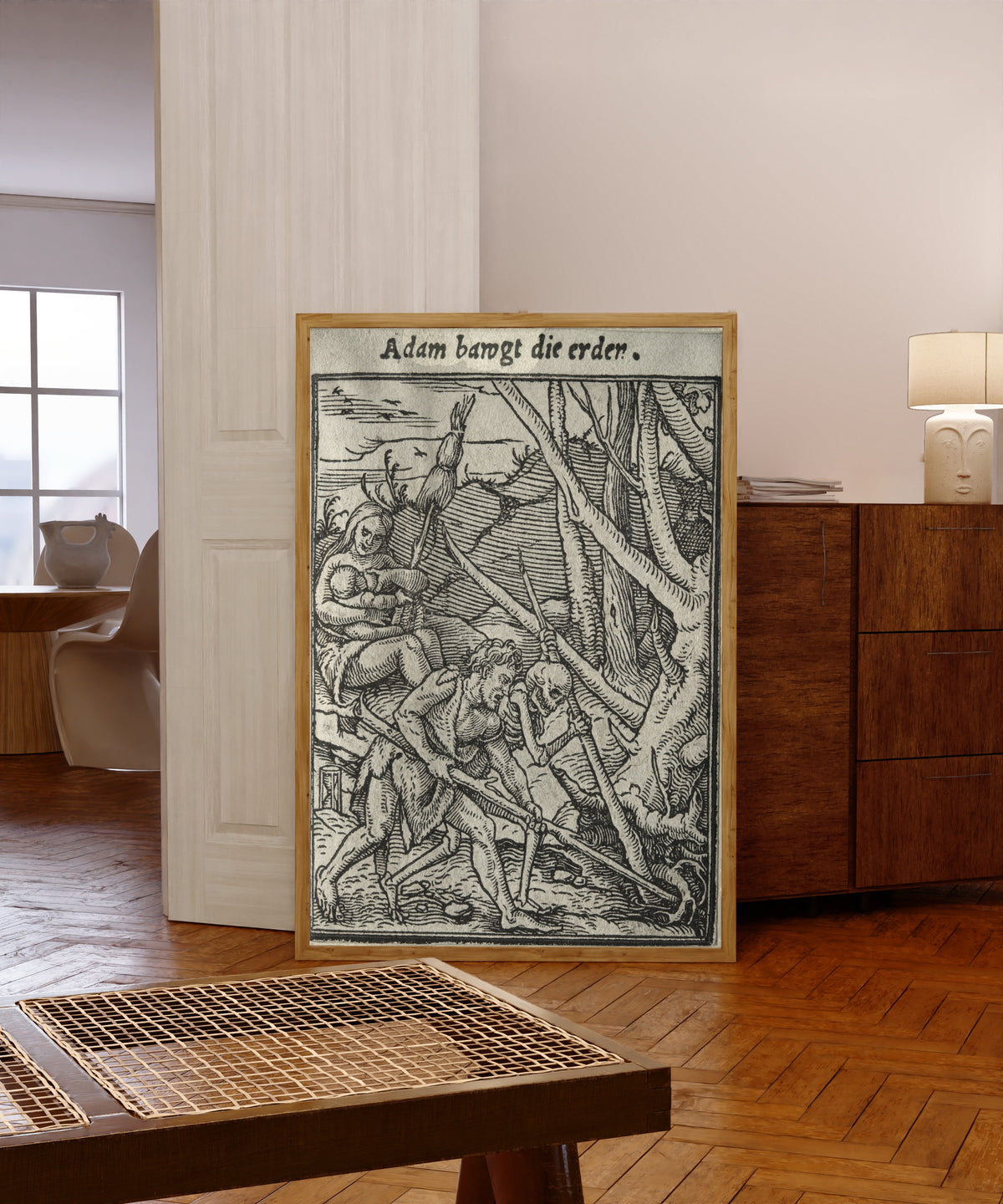 Framed art print of The Dance of Death: Adam bawgt die erden… by Hans Holbein the Younger, in a light wood frame leaning in a warm room with a parquet floor