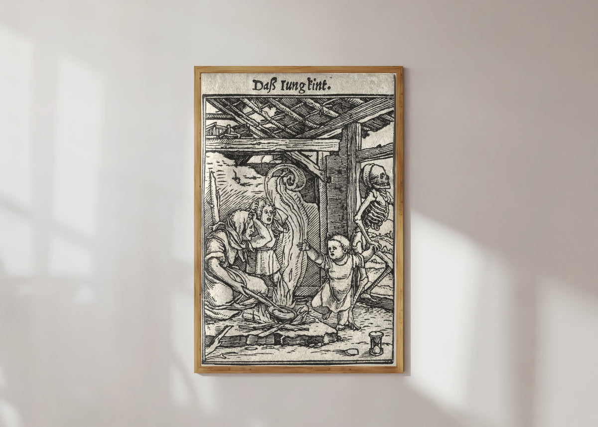 Framed art print of The Dance of Death: Daß Iung kint (The Child) by Hans Holbein the Younger, in a light wood frame on a sunlit white wall