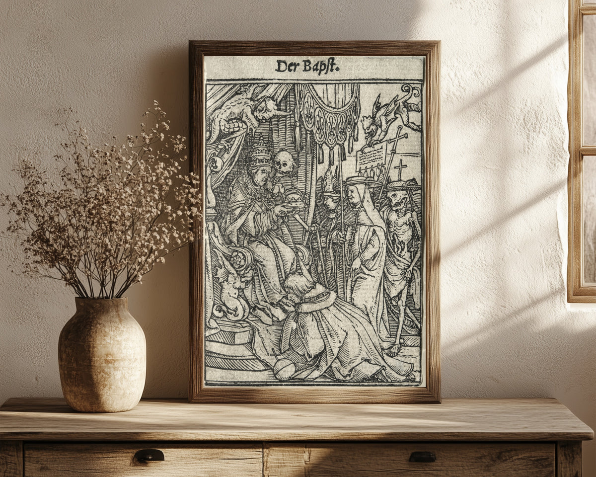 Framed art print of The Dance of Death: Der Bapst (The Pope) by Hans Holbein the Younger, in a dark wood frame leaning on a rustic console beside dried flowers