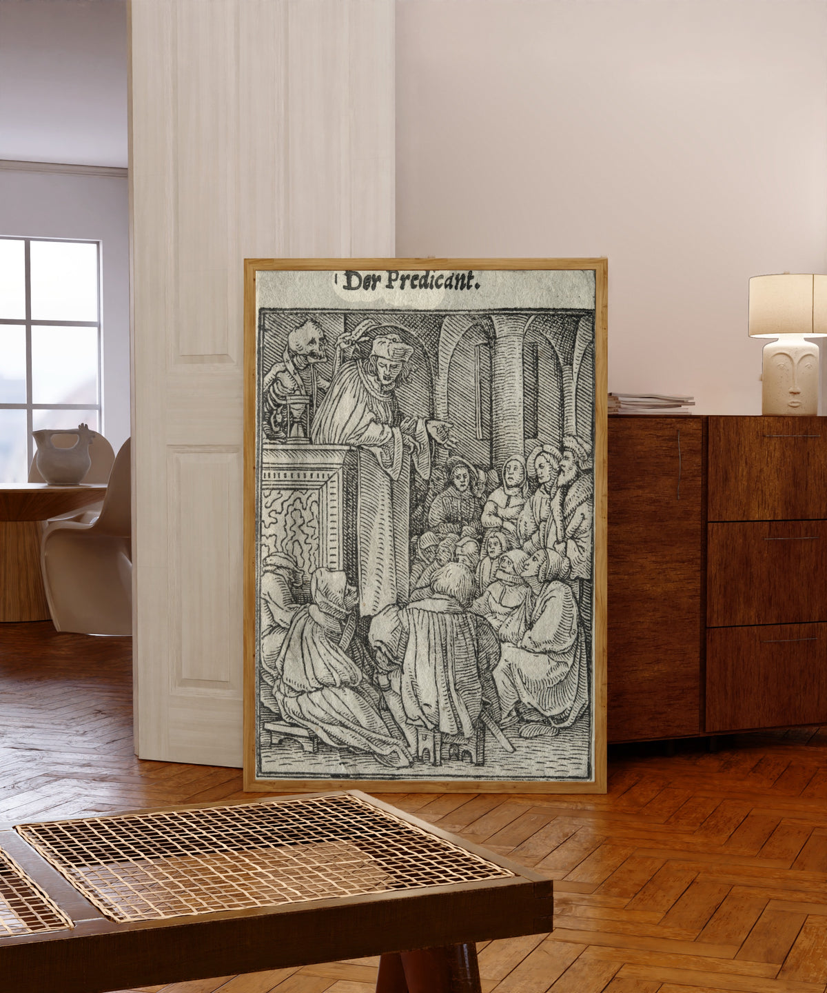 Framed art print of The Dance of Death: Der Predicant (The… by Hans Holbein the Younger, in a light wood frame leaning in a warm room with a parquet floor