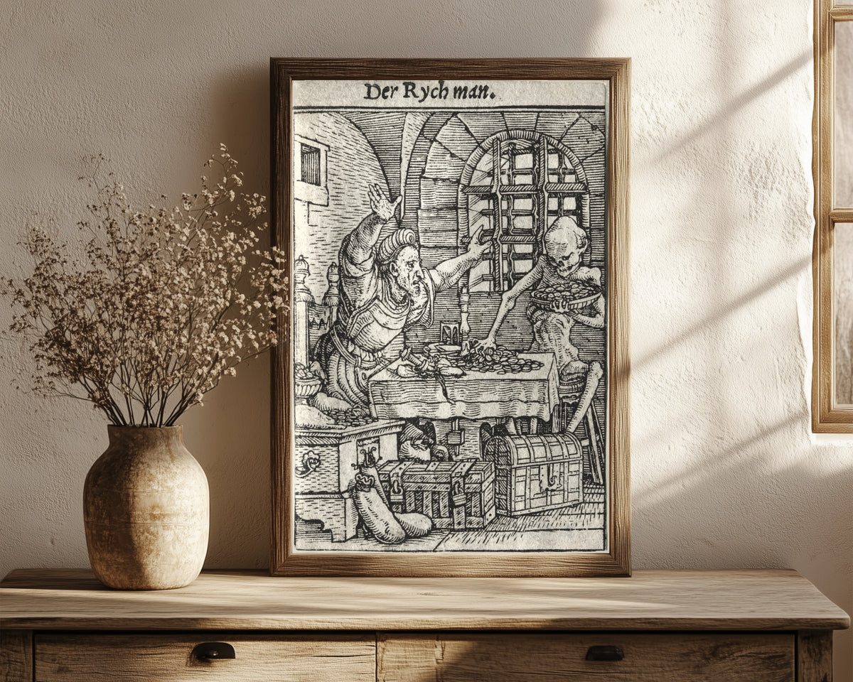Framed art print of The Dance of Death: Der Rych man (The… by Hans Holbein the Younger, in a dark wood frame leaning on a rustic console beside dried flowers