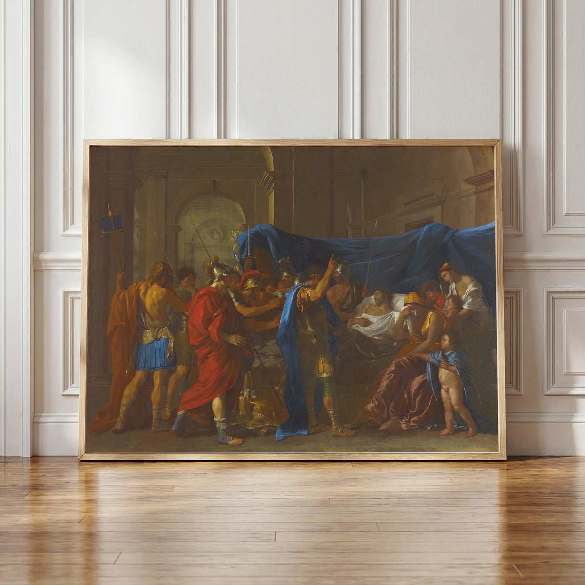 Framed art print of The Death of Germanicus by Nicolas Poussin, in a light wood frame leaning against a panelled white wall
