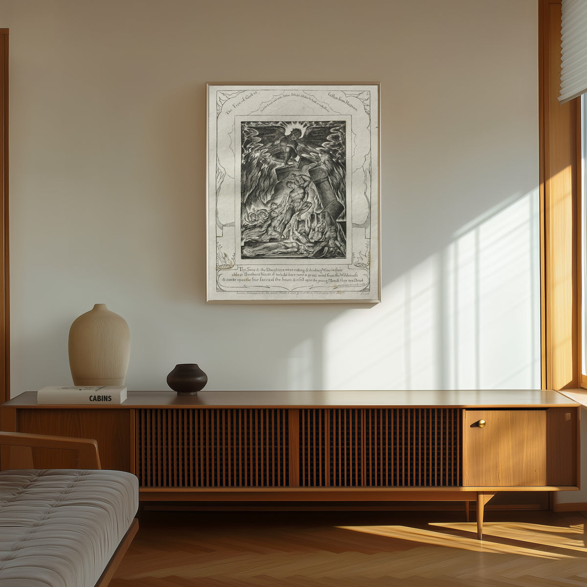 Framed art print of The Destruction of Job's Sons (Book of Job, Plate 3) by William Blake, in a thin light frame on a sunlit wall above a wooden sideboard