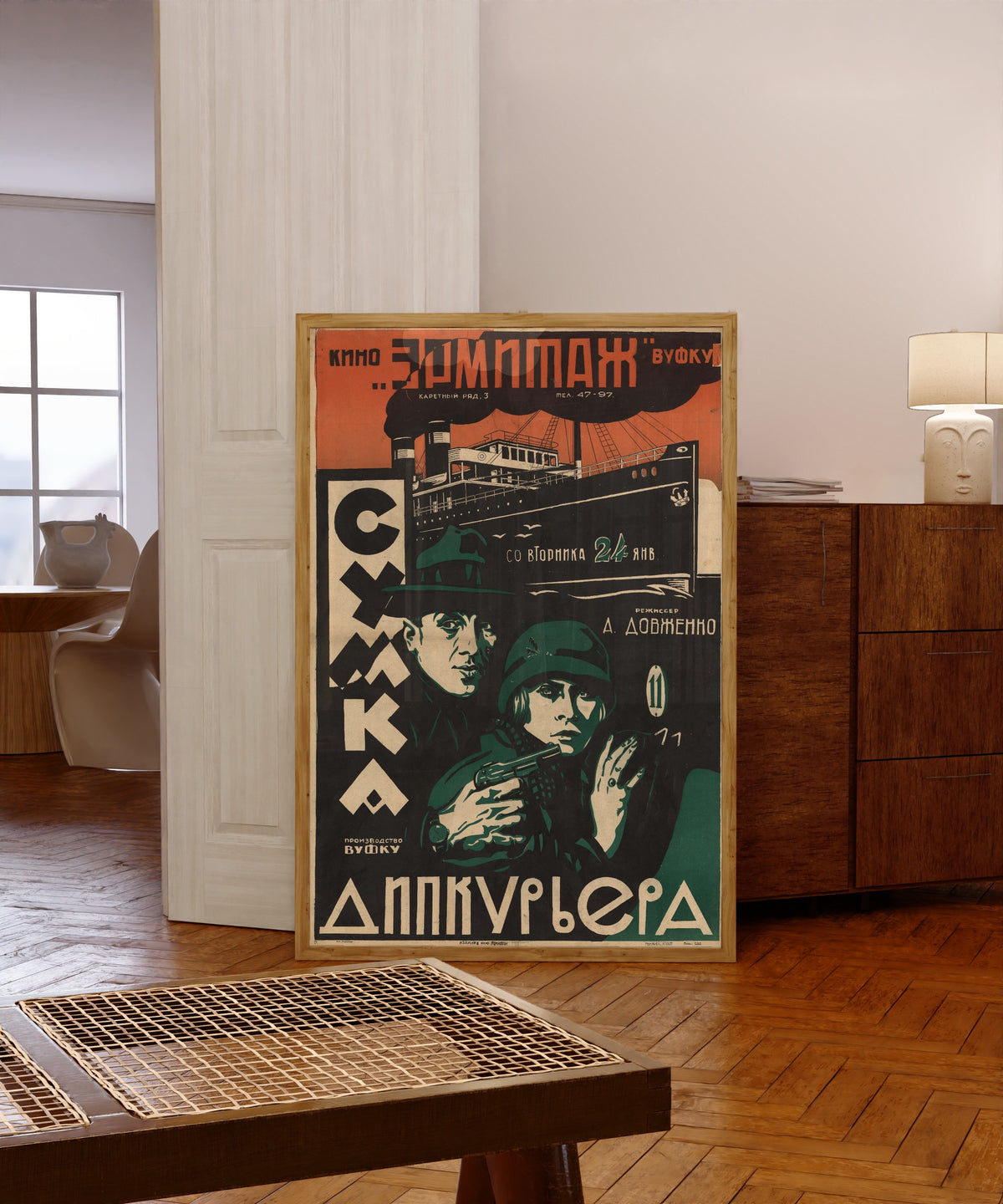 Framed art print of The Diplomatic Pouch, in a light wood frame leaning in a warm room with a parquet floor