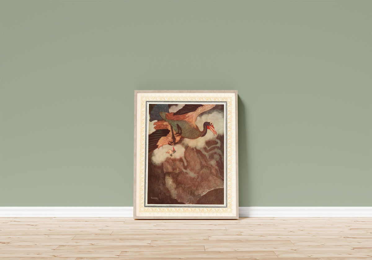 Framed art print of The Episode of the Rokh by Edmund Dulac, in a light wood frame leaning on a sage green wall above a wooden floor