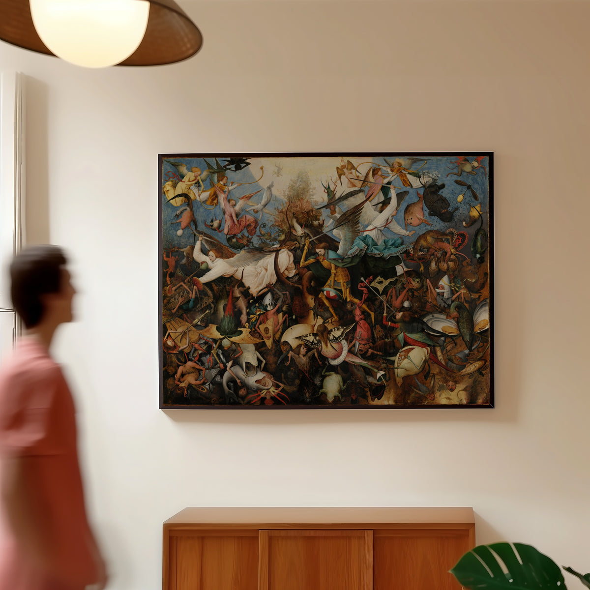 Framed art print of The Fall of the Rebel Angels by Pieter Bruegel the Elder, in a slim black frame on a warm wall in a sunlit room