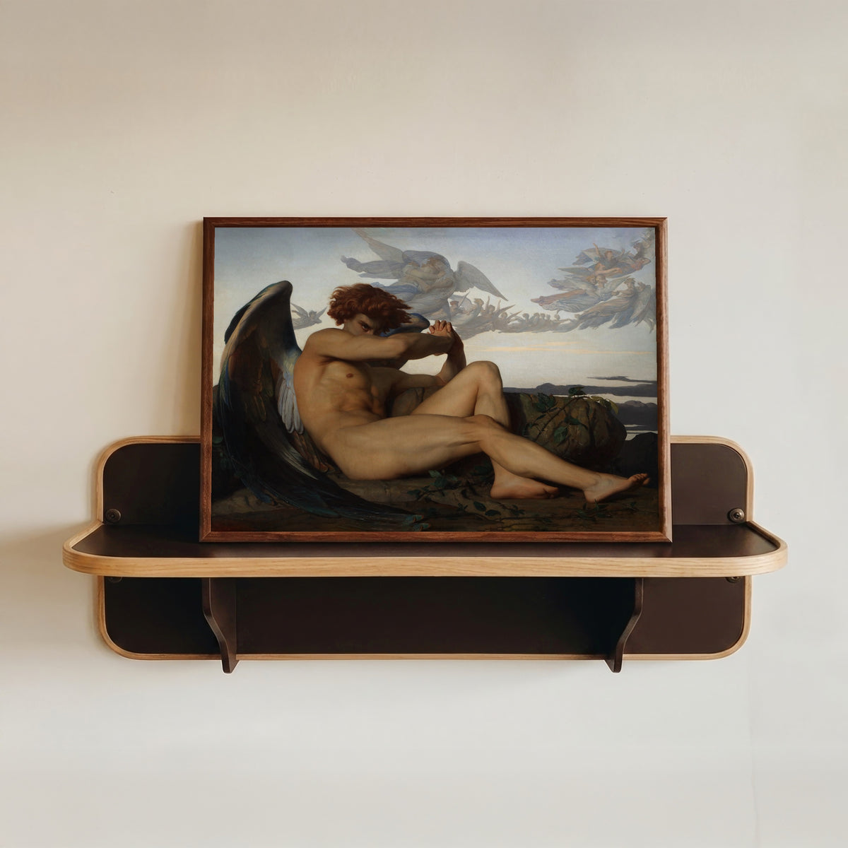 Framed art print of The Fallen Angel by Alexandre Cabanel, in a dark wood frame resting on a wall shelf