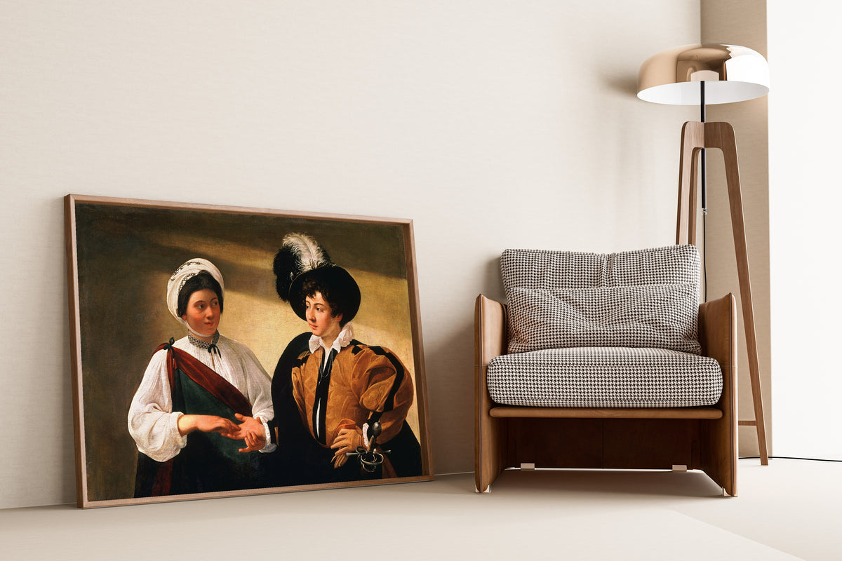 Framed art print of The Fortune Teller by Caravaggio, leaning against a wall beside an armchair and a floor lamp