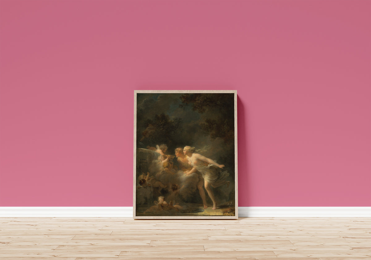 Framed art print of The Fountain of Love by Jean-Honoré Fragonard, in a light wood frame leaning on a pink wall above a wooden floor