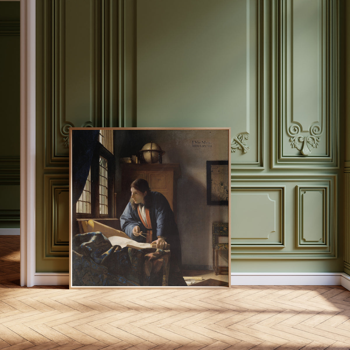 Framed art print of The Geographer by Johannes Vermeer, leaning against olive-green panelling on a herringbone floor