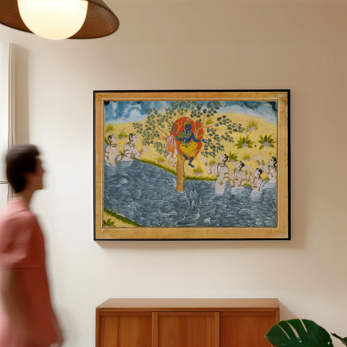 Framed art print of The Gopis Plead with Krishna to Return Their Clothing by Bikaner school, in a slim black frame on a warm wall in a sunlit room