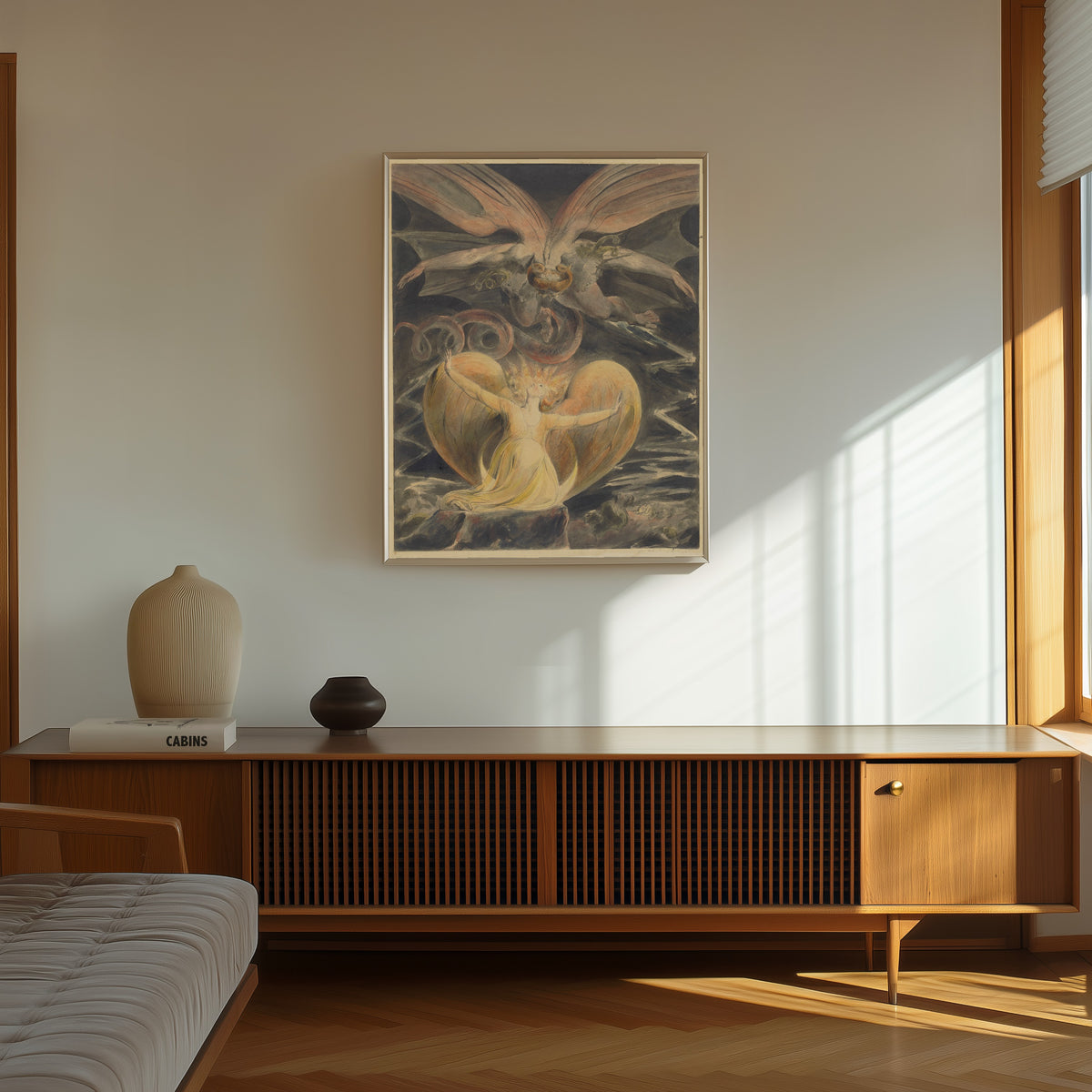 Framed art print of The Great Red Dragon and the Woman Clothed with the Sun by William Blake, in a thin light frame on a sunlit wall above a wooden sideboard