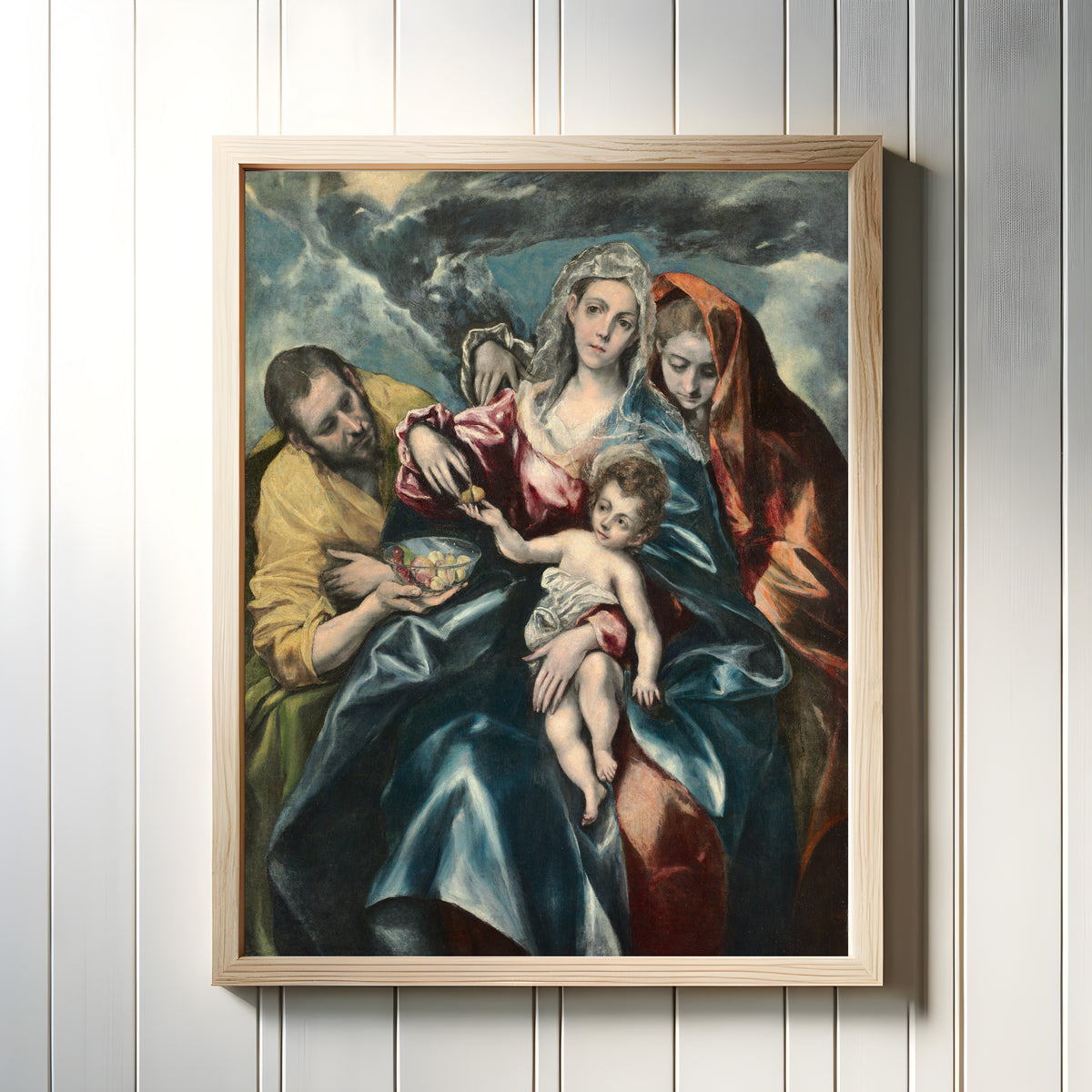 Framed art print of The Holy Family with Mary Magdalen by El Greco, in a light wood frame on a white panelled wall