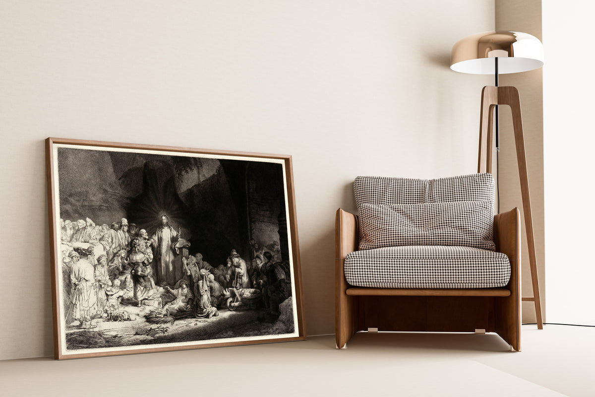 Framed art print of The Hundred Guilder Print by Rembrandt van Rijn, leaning against a wall beside an armchair and a floor lamp