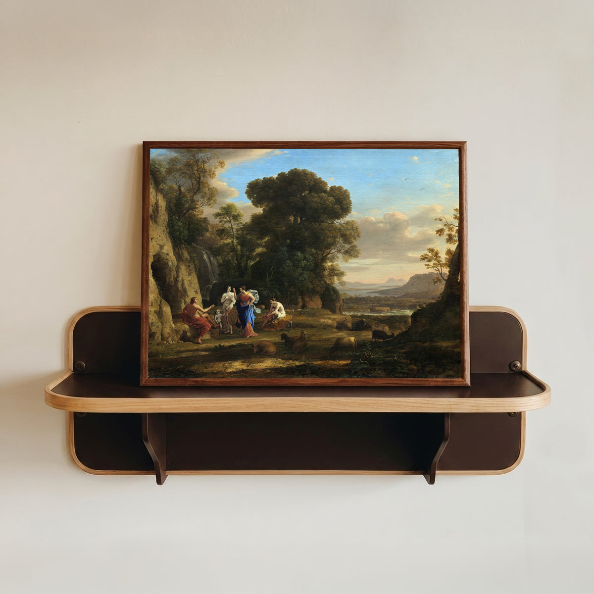 Framed art print of The Judgment of Paris by Claude Lorrain, in a dark wood frame resting on a wall shelf