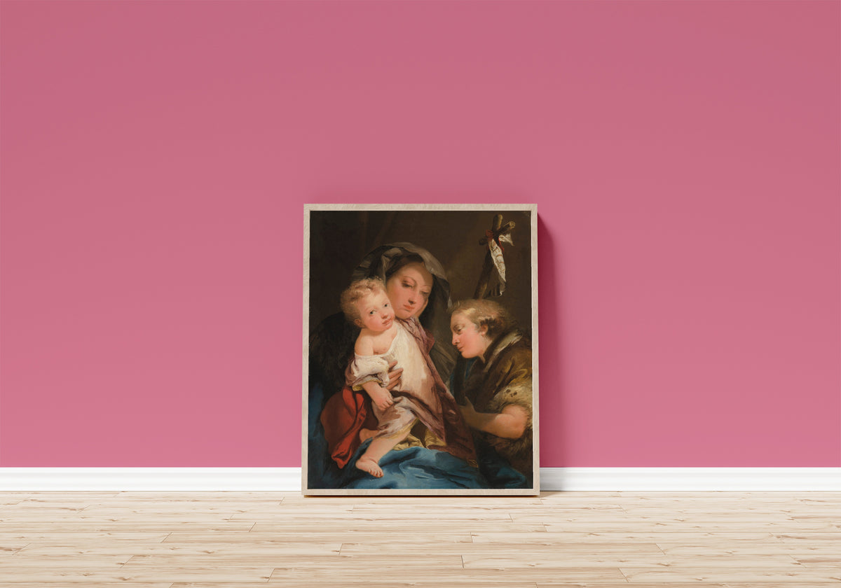 Framed art print of The Madonna and Child with the Infant… by Giovanni Domenico Tiepolo, in a light wood frame leaning on a pink wall above a wooden floor