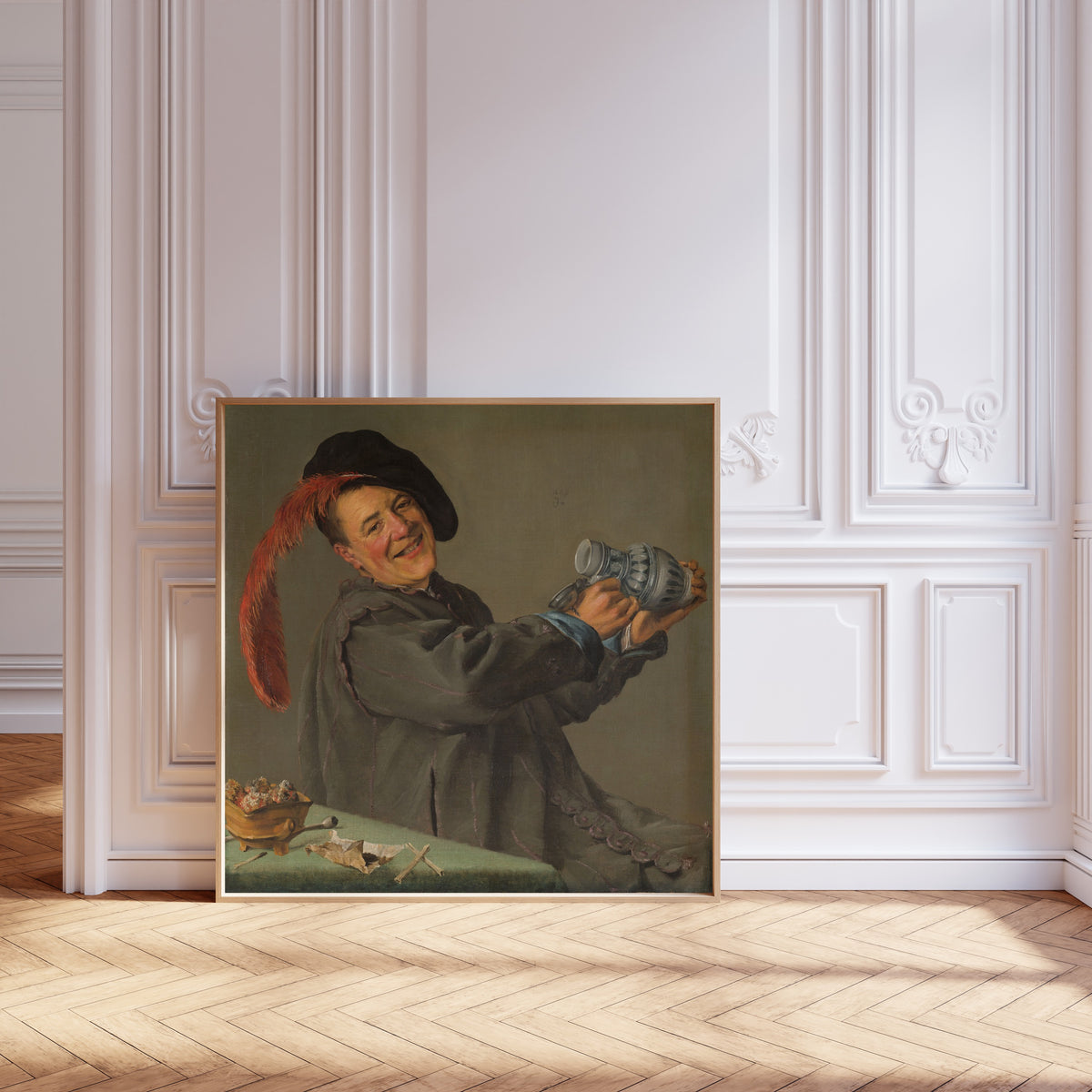 Framed art print of The Merry Drinker by Judith Leyster, leaning against pale pink panelling on a herringbone floor