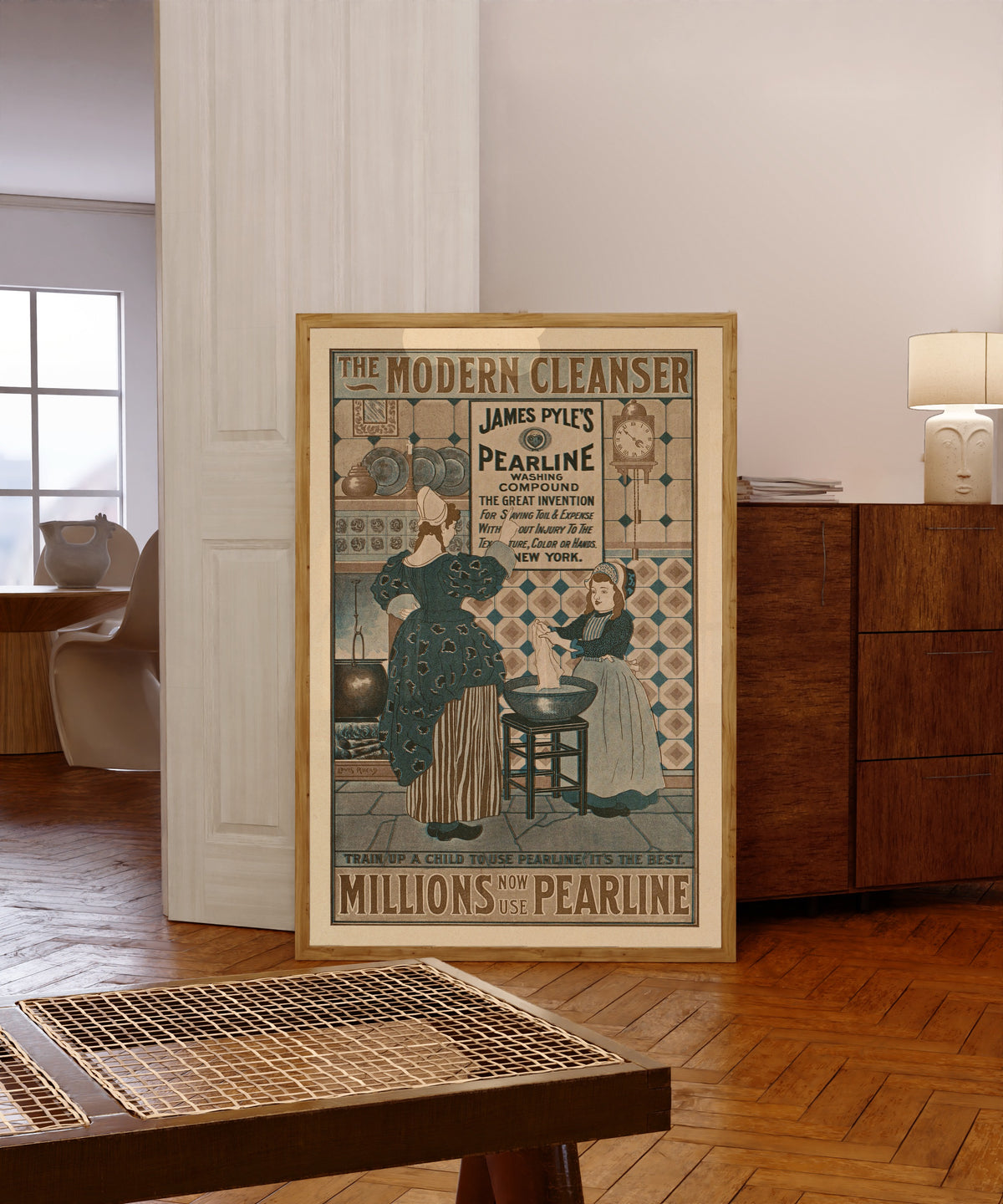 Framed art print of The Modern Cleanser, Millions Now Use Pearline by Louis Rhead, in a light wood frame leaning in a warm room with a parquet floor