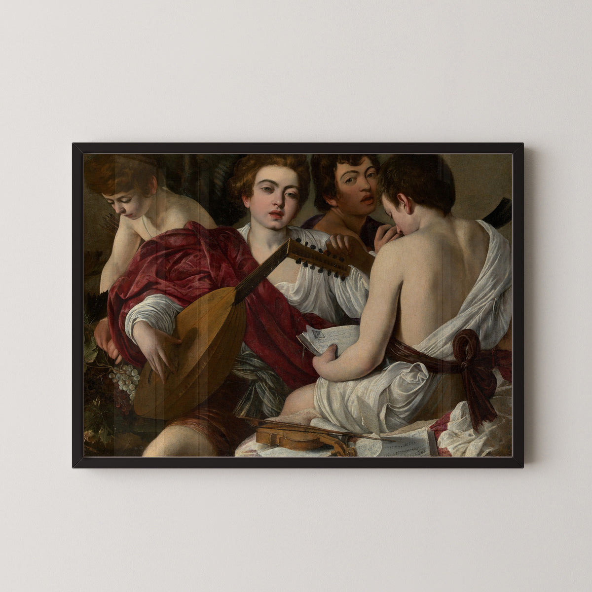 Framed art print of The Musicians by Caravaggio, in a black frame on a pale wall