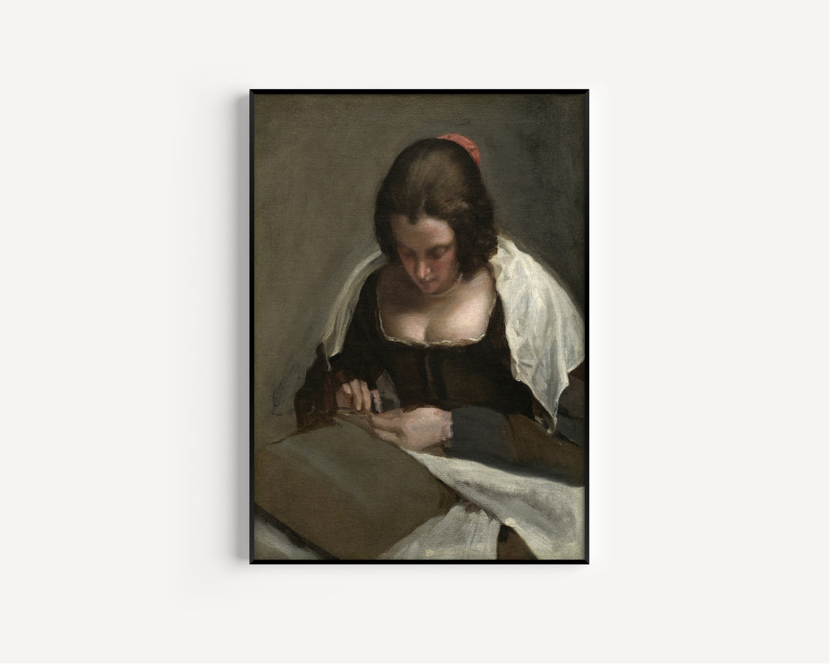 Framed art print of The Needlewoman by Diego Velázquez, in a slim black frame on a plain white wall