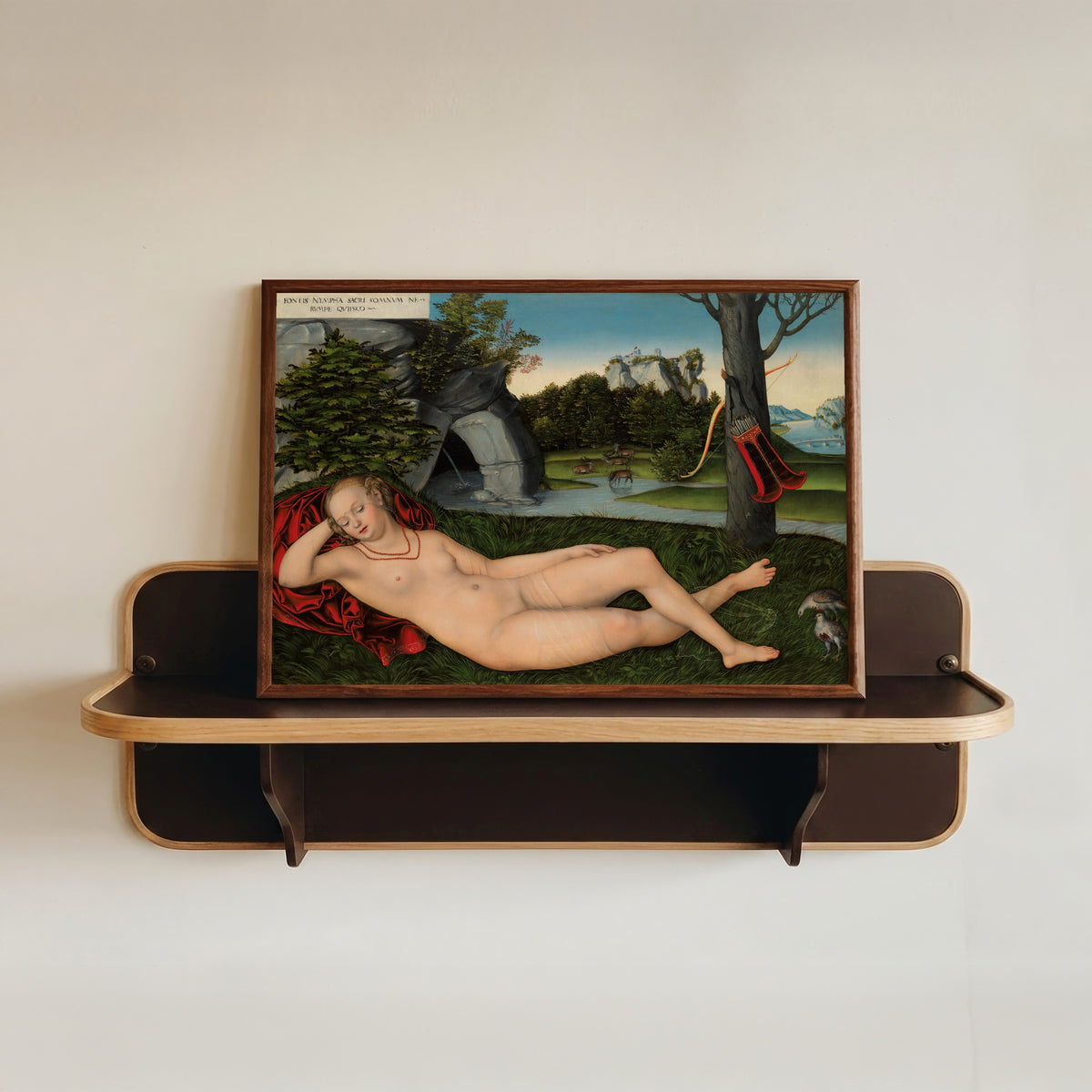 Framed art print of The Nymph of the Spring by Lucas Cranach the Elder, in a dark wood frame resting on a wall shelf