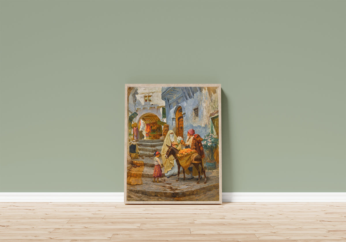 Framed art print of The Orange Seller by Frederick Arthur Bridgman, in a light wood frame leaning on a sage green wall above a wooden floor
