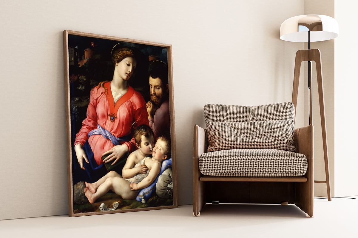 Framed art print of The Panciatichi Holy Family by Bronzino, leaning against a wall beside an armchair and a floor lamp