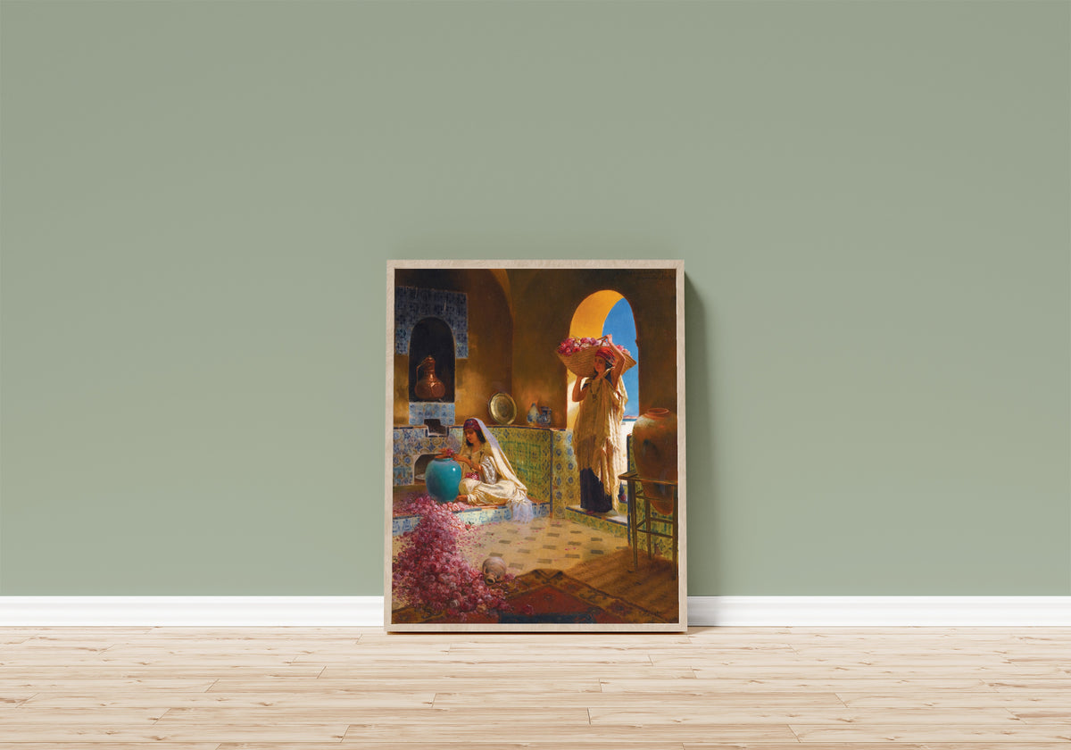 Framed art print of The Perfume Makers by Rudolf Ernst, in a light wood frame leaning on a sage green wall above a wooden floor