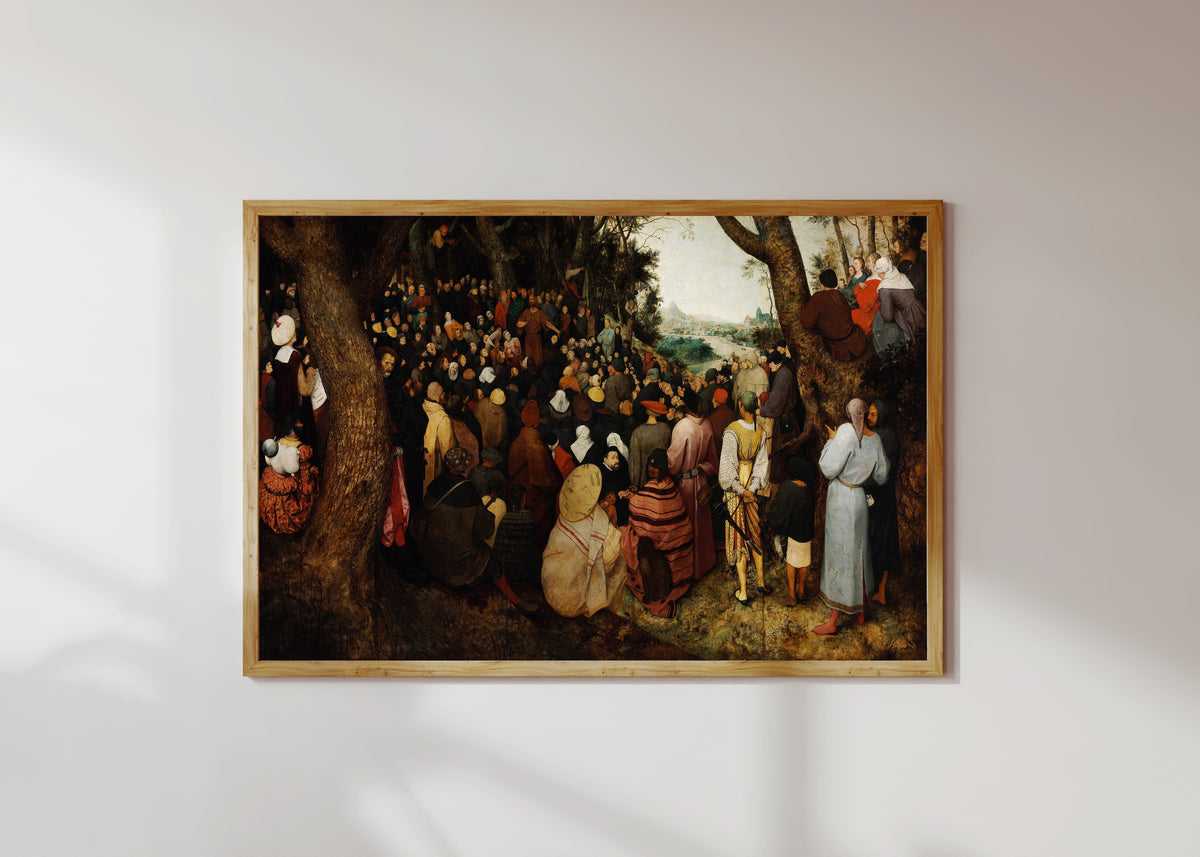 Framed art print of The Preaching of Saint John the Baptist by Pieter Bruegel the Elder, in a light wood frame on a sunlit white wall