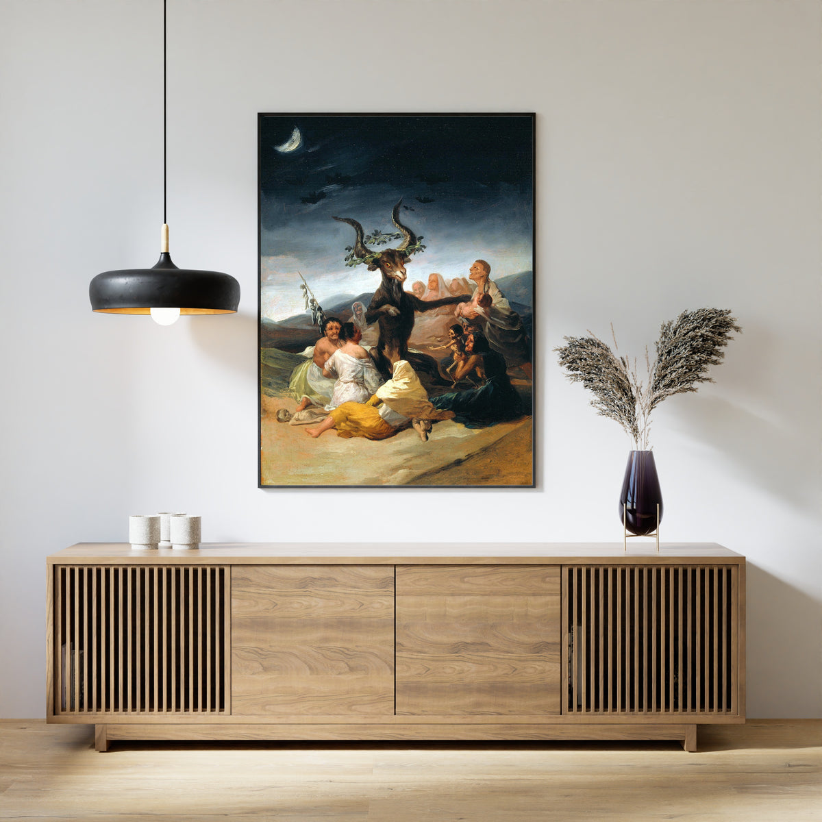 Framed art print of The Sabbath of Witches by Francisco de Goya, above a slatted wood sideboard