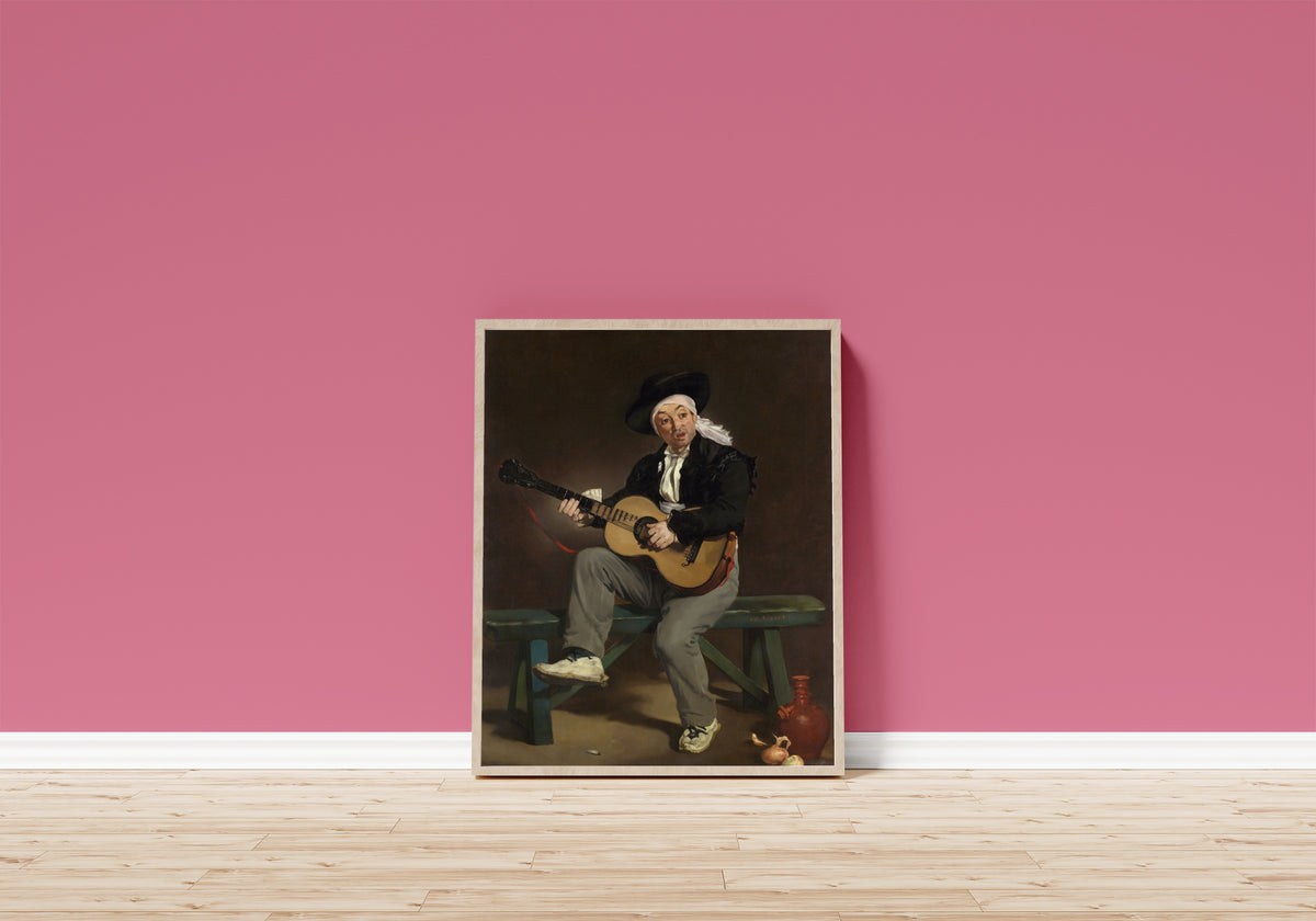 Framed art print of The Spanish Singer by Édouard Manet, in a light wood frame leaning on a pink wall above a wooden floor