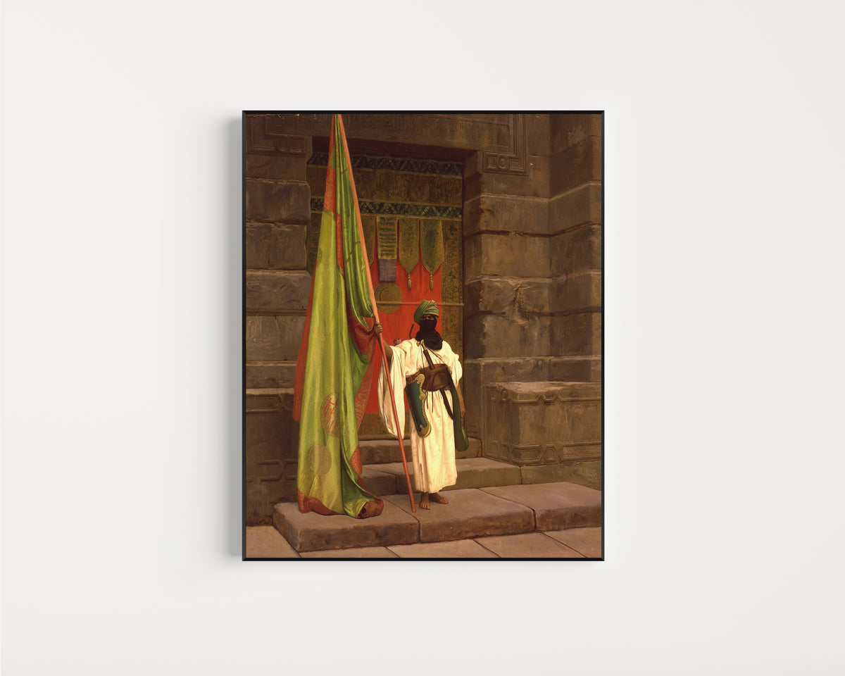 Framed art print of The Standing Bearer, Unfolding the Holy Flag by Jean-Léon Gérôme, in a slim black frame on a plain white wall