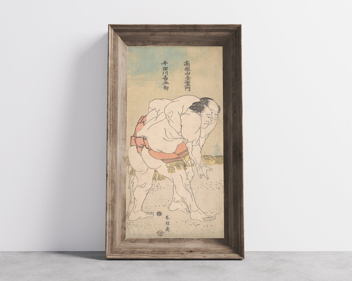 Framed art print of The Sumo Wrestlers Takaneyama Yoichiemon and Sendagawa… by Katsushika Hokusai, in a wide wooden frame leaning against a concrete wall