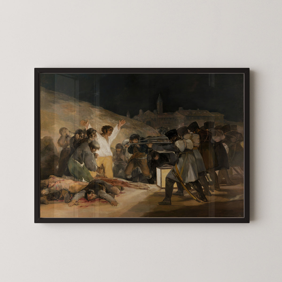 Framed art print of The Third of May 1808 by Francisco de Goya, in a black frame on a pale wall
