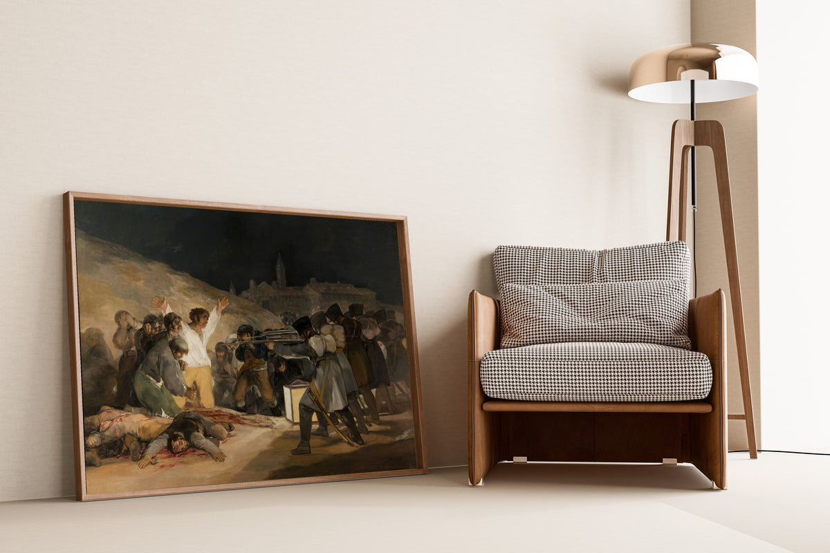 Framed art print of The Third of May 1808 by Francisco de Goya, leaning against a wall beside an armchair and a floor lamp