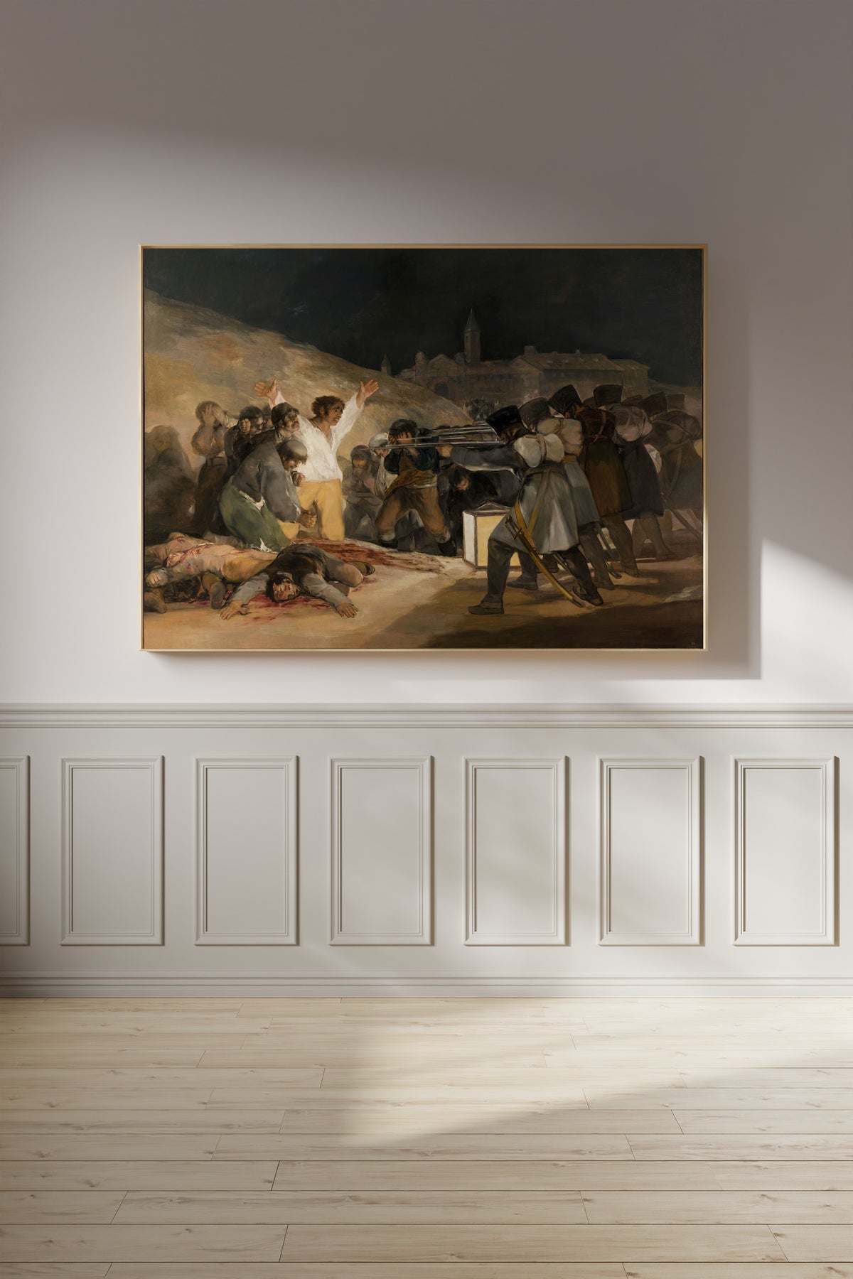 Framed art print of The Third of May 1808 by Francisco de Goya, on a panelled wall in afternoon light