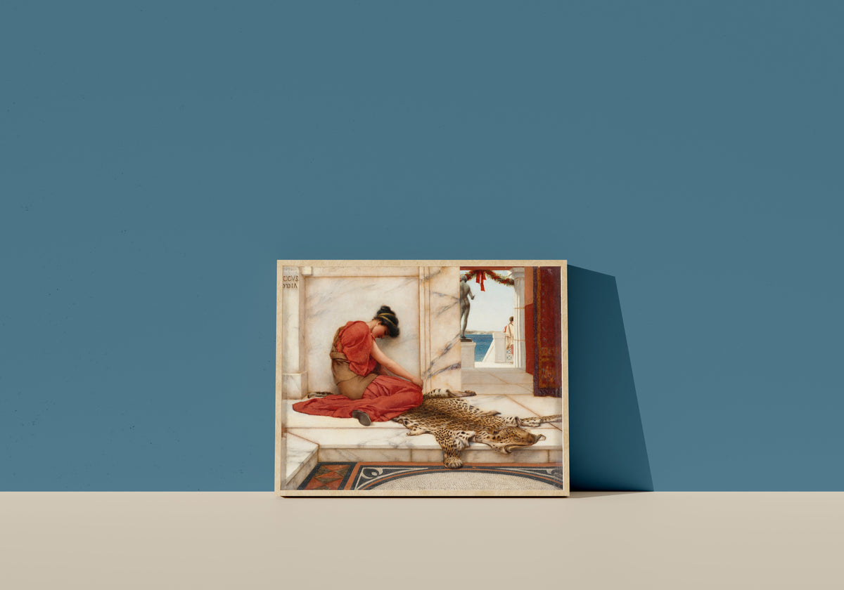 Framed art print of The Tiff by John William Godward, in a light wood frame leaning on a blue wall