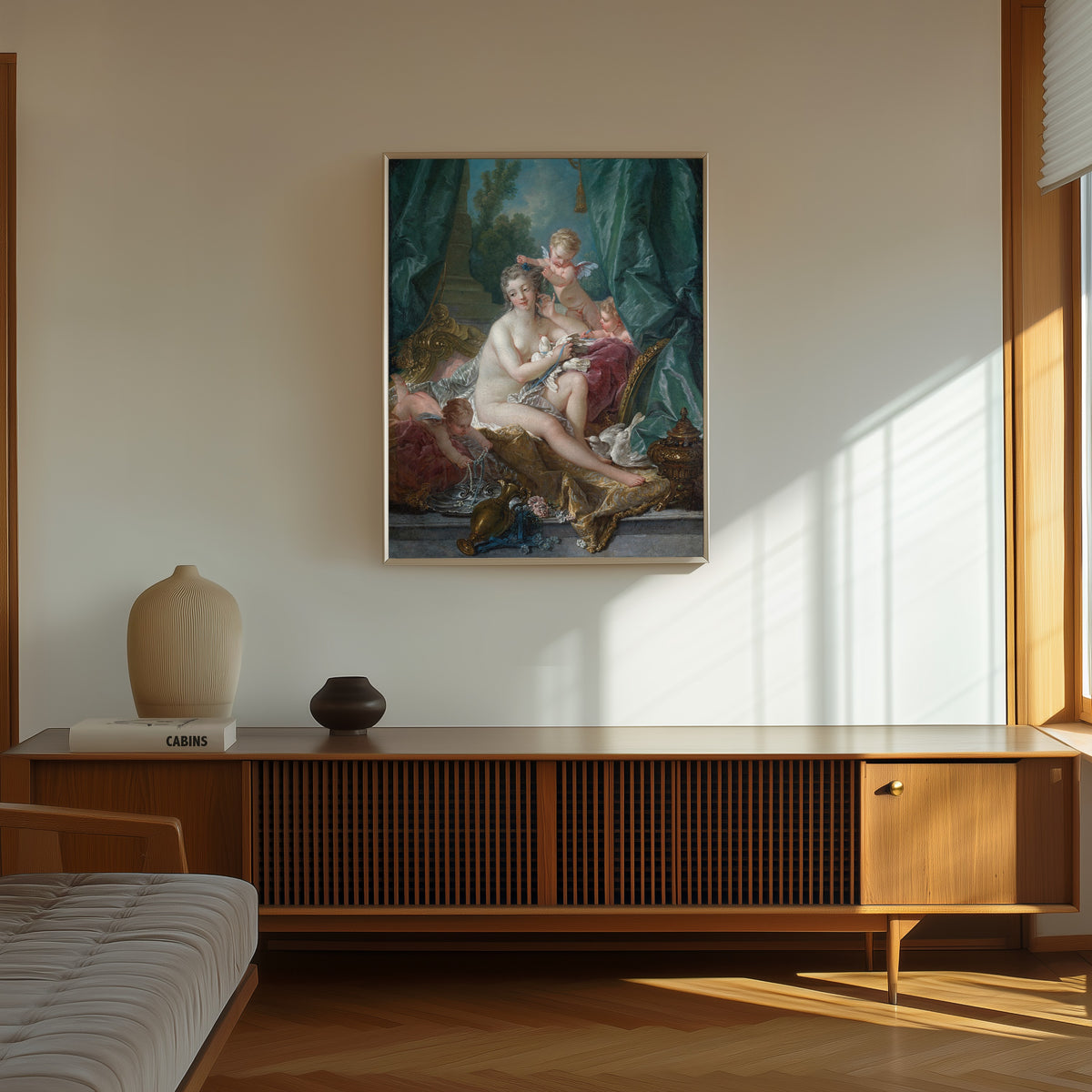 Framed art print of The Toilette of Venus by François Boucher, in a thin light frame on a sunlit wall above a wooden sideboard