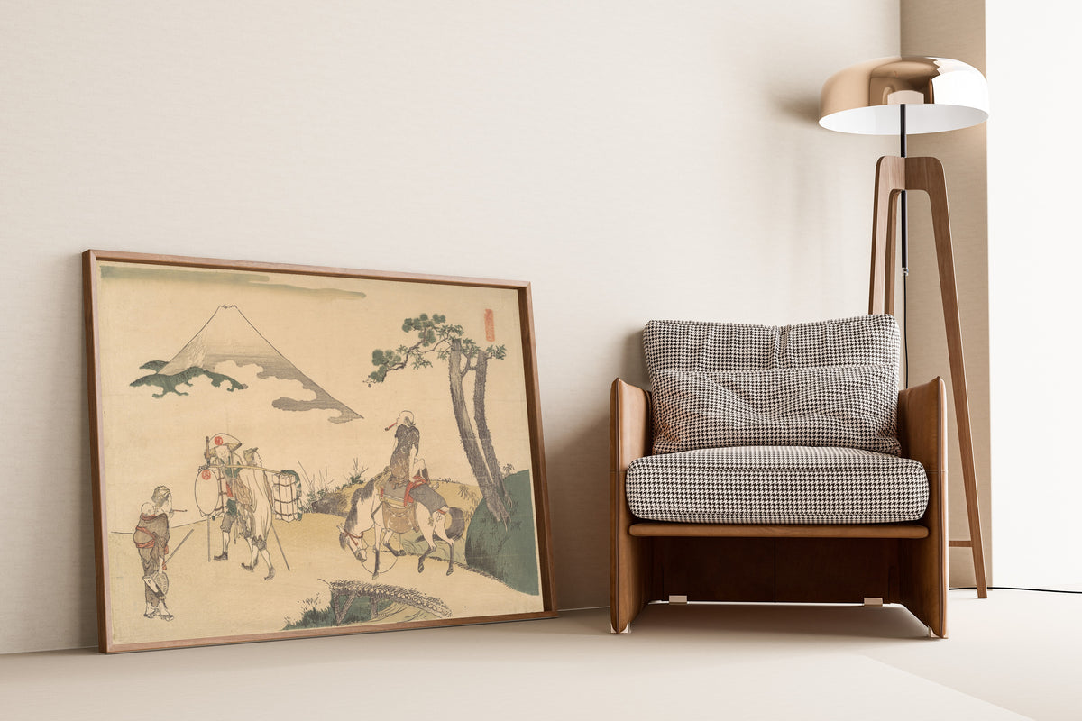 Framed art print of The Top of Mount Fuji by Katsushika Hokusai, leaning against a wall beside an armchair and a floor lamp