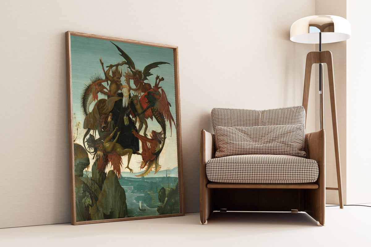 Framed art print of The Torment of Saint Anthony by Michelangelo, leaning against a wall beside an armchair and a floor lamp
