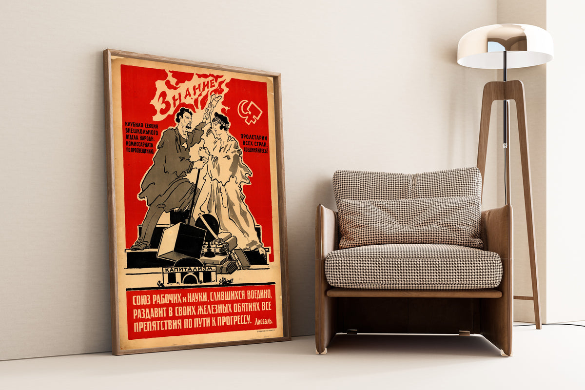 Framed art print of The Union of Workers and Science, Merged into One, leaning against a wall beside an armchair and a floor lamp