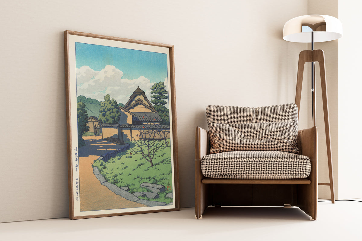 Framed art print of The West Village, Horyuji Temple by Kawase Hasui, leaning against a wall beside an armchair and a floor lamp
