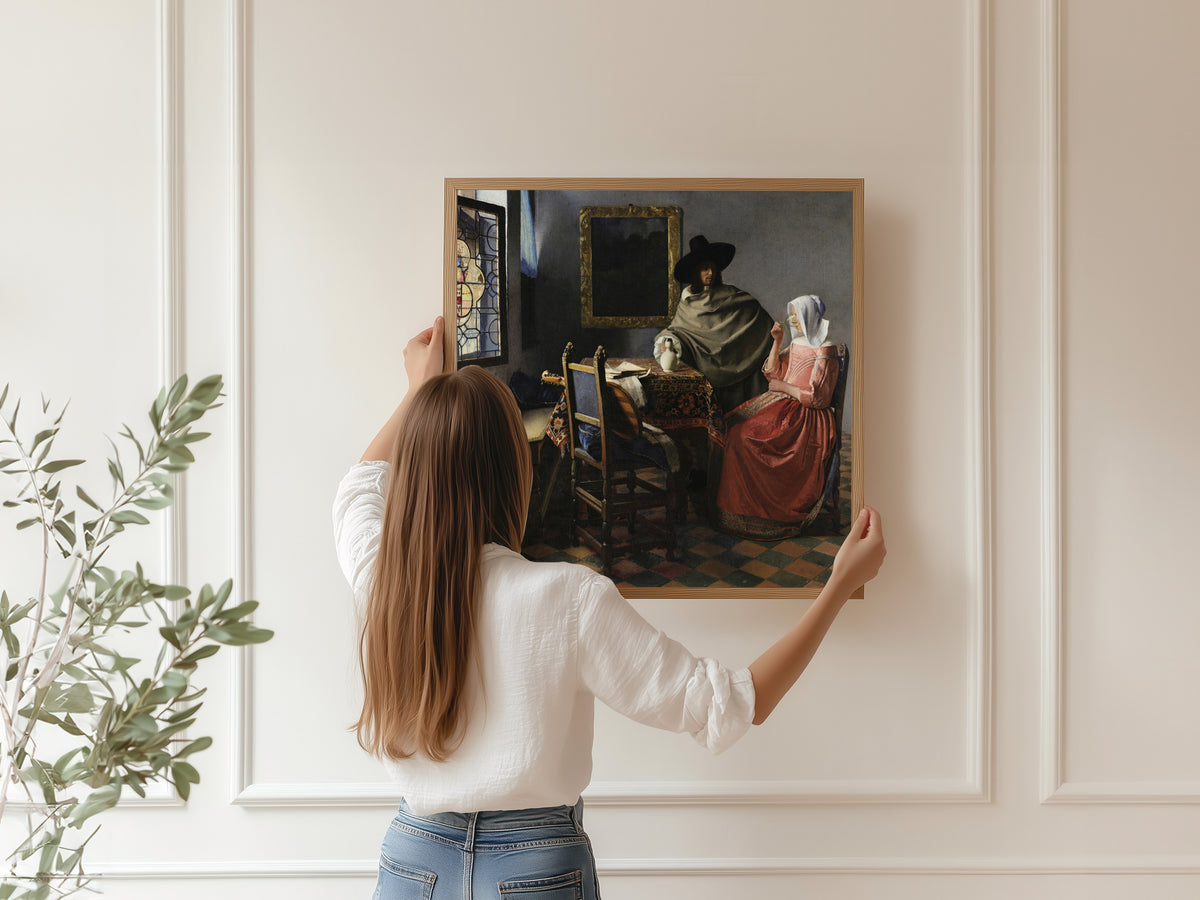 Framed art print of The Wine Glass by Johannes Vermeer, hung on a panelled wall