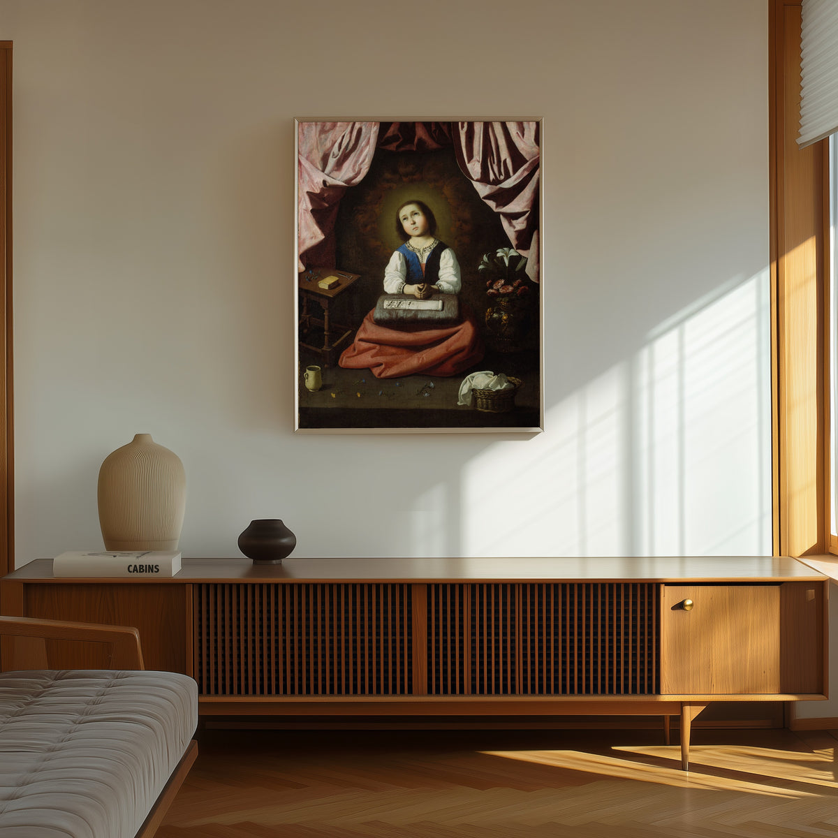 Framed art print of The Young Virgin by Francisco de Zurbarán, in a thin light frame on a sunlit wall above a wooden sideboard